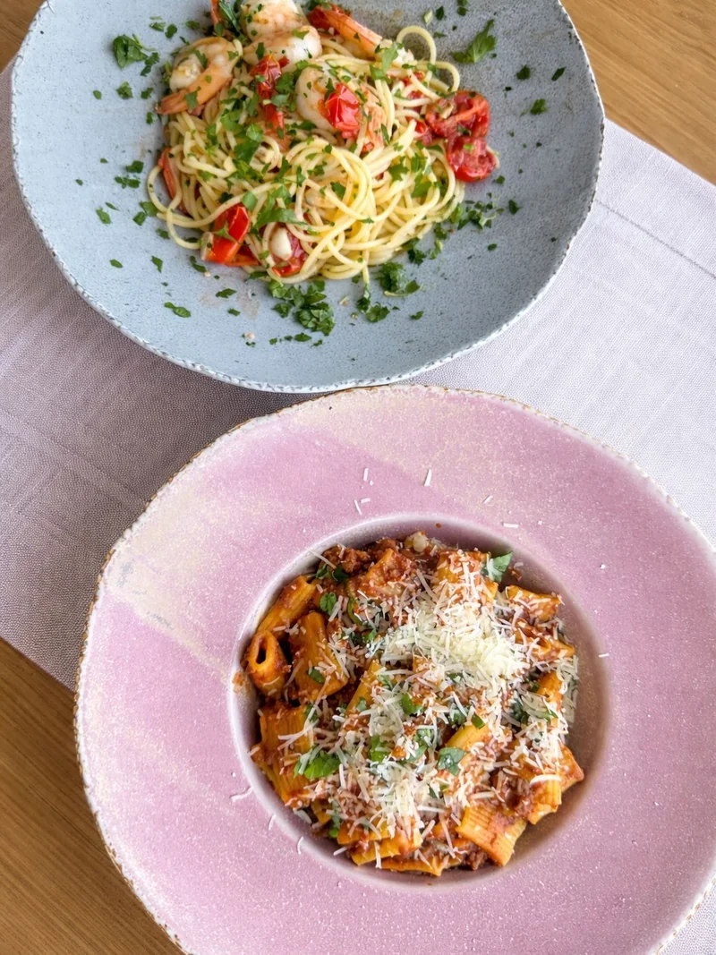 Spaghetti z krewetkami i rigatoni bolognese w kolorowych miskach